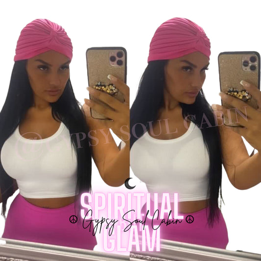 A woman wearing a pink Bohemian head wrap with a white top and pink trousers.