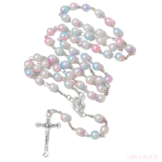 A rosary necklace featuring iridescent pastel pearls in pink, blue, and white, connected by silver-tone chains and a silver-tone crucifix pendant, shown on a plain white background.