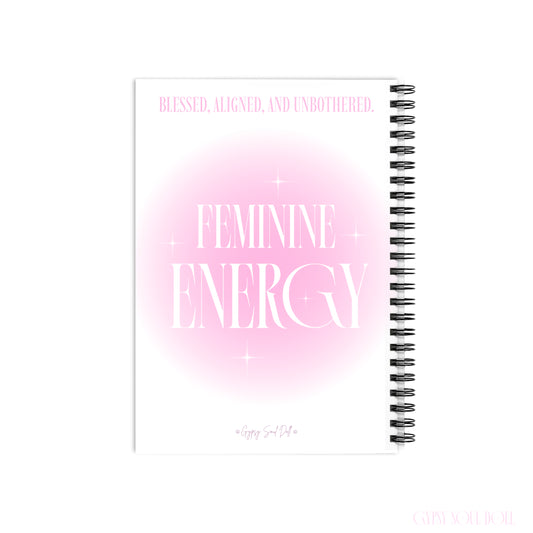 A back cover mockup of a Gypsy Soul Doll manifestation journal featuring a soft pink aura gradient centre with white sparkle stars and tall editorial typography reading Feminine Energy and Blessed Aligned and Unbothered at the top with a signature logo footer at the bottom centred over a white backdrop.