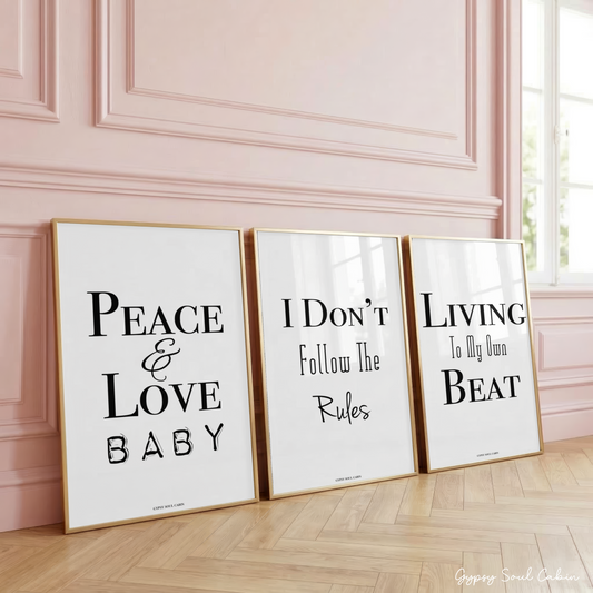 Set of three minimalist black and white typography prints featuring motivational and sassy quotes about independence and individuality, framed on a wooden floor against a pink panelled wall.