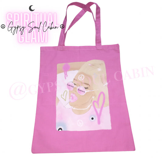 Close-up view of a bright pink canvas tote bag featuring an artistic female graphic wearing Limited Edition sunglasses and eating a pink lollipop.