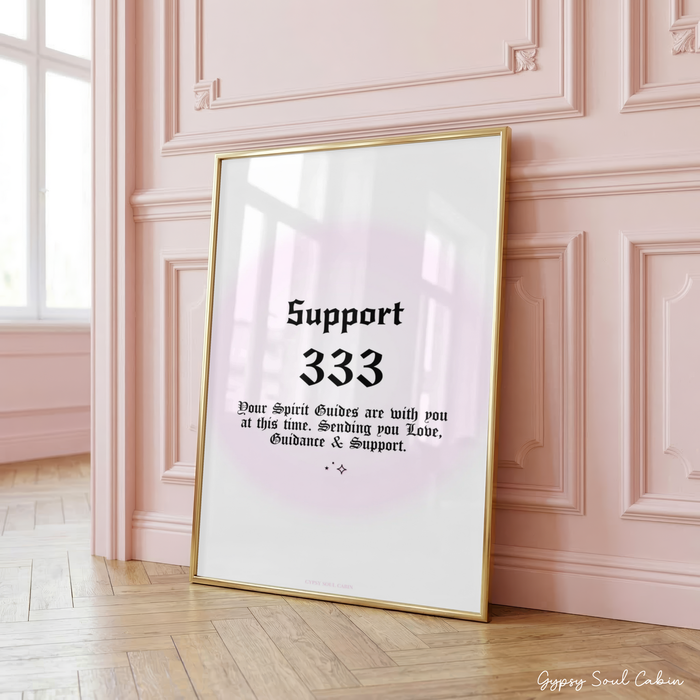 Minimalist A4 manifestation wall art print featuring the word Support and 333 angel number in bold black gothic typography over a soft pastel pink aura gradient backdrop, framed on a wooden floor against a pink panelled wall.