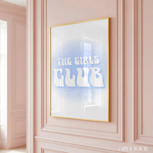 Retro wavy typography print reading The Girls Club with a white female symbol centred under a soft blue gradient aura halo in a large gold frame hanging on a classic panelled pink wall.