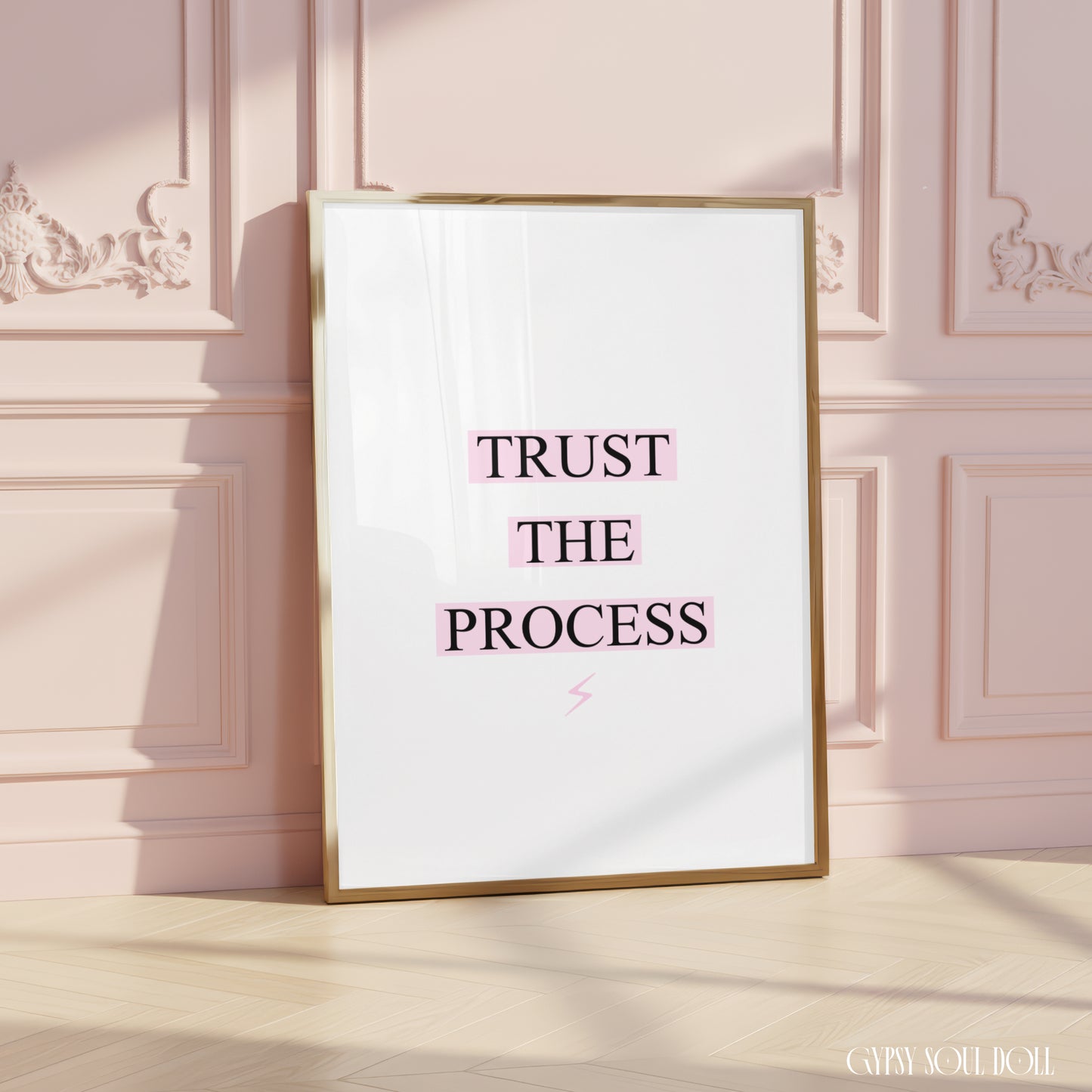 Minimalist motivation wall decor print featuring the quote "Trust The Process," with pink-highlighted text boxes and a tiny pink lightning-bolt icon at the bottom.