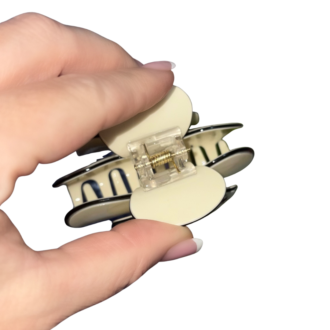 Top view of an open cream camellia flower hair clip showing the durable gold internal spring mechanism.