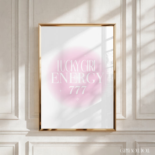A4 poster print featuring "Lucky Girl Energy" and "+ 777" in clean white editorial typography over a soft pink radial aura gradient background with mini sparkles by Gypsy Soul Doll.