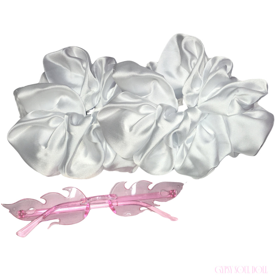 A set of two large white satin hair scrunchies and a translucent pink plastic hair clip, displayed on a clean white background.