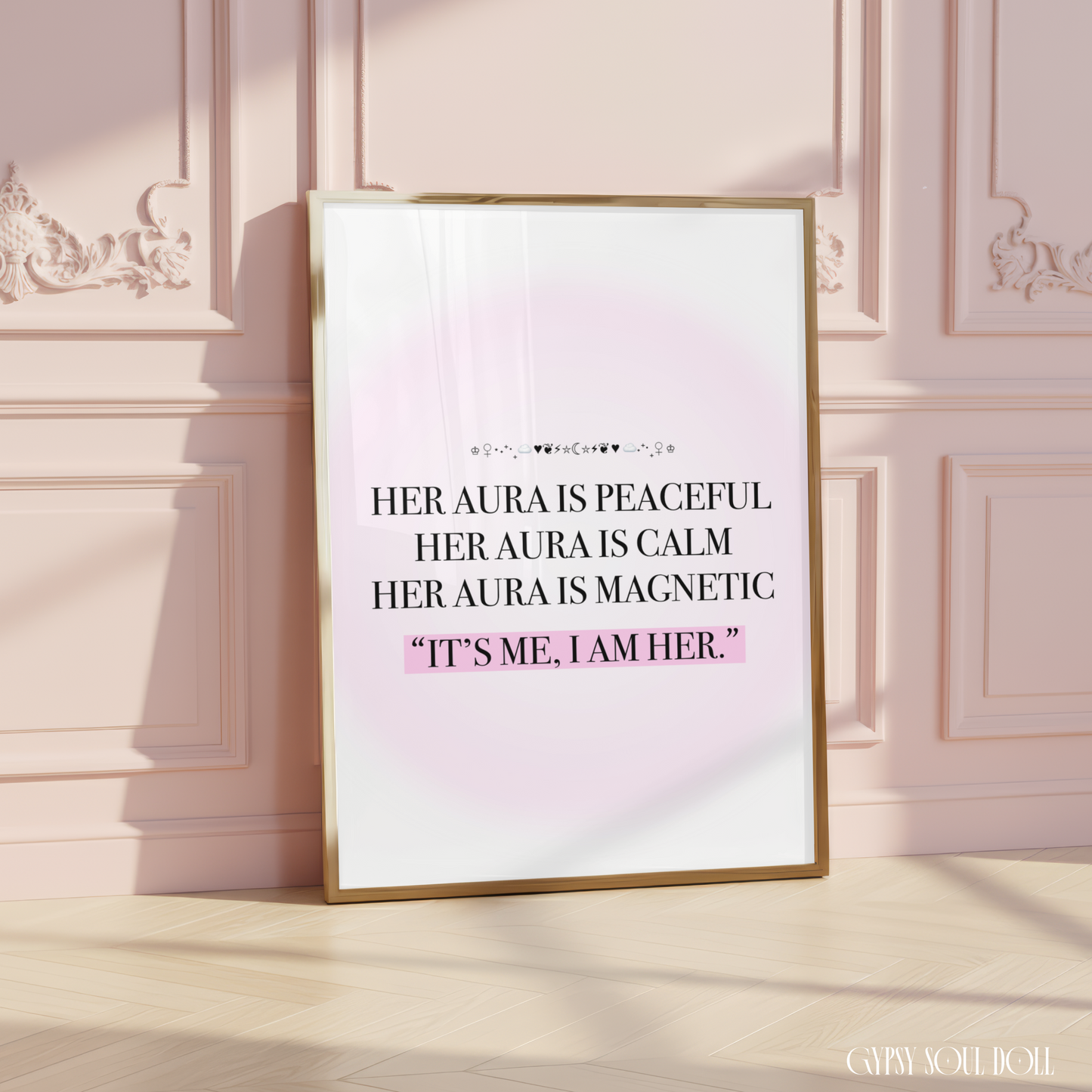 A framed typographic art print has a white background with a soft pink glow and black text reading, "HER AURA IS PEACFUL HER AURA IS CALM HER AURA IS MAGNETIC 'IT'S ME, I AM HER.