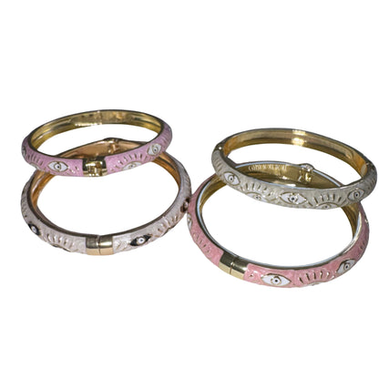 Four decorative bangles stacked together on a plain white background. Two bangles are light pink with gold-toned inner walls and silver-toned outer walls, featuring small white and black eye motifs by Gypsy Soul Doll.