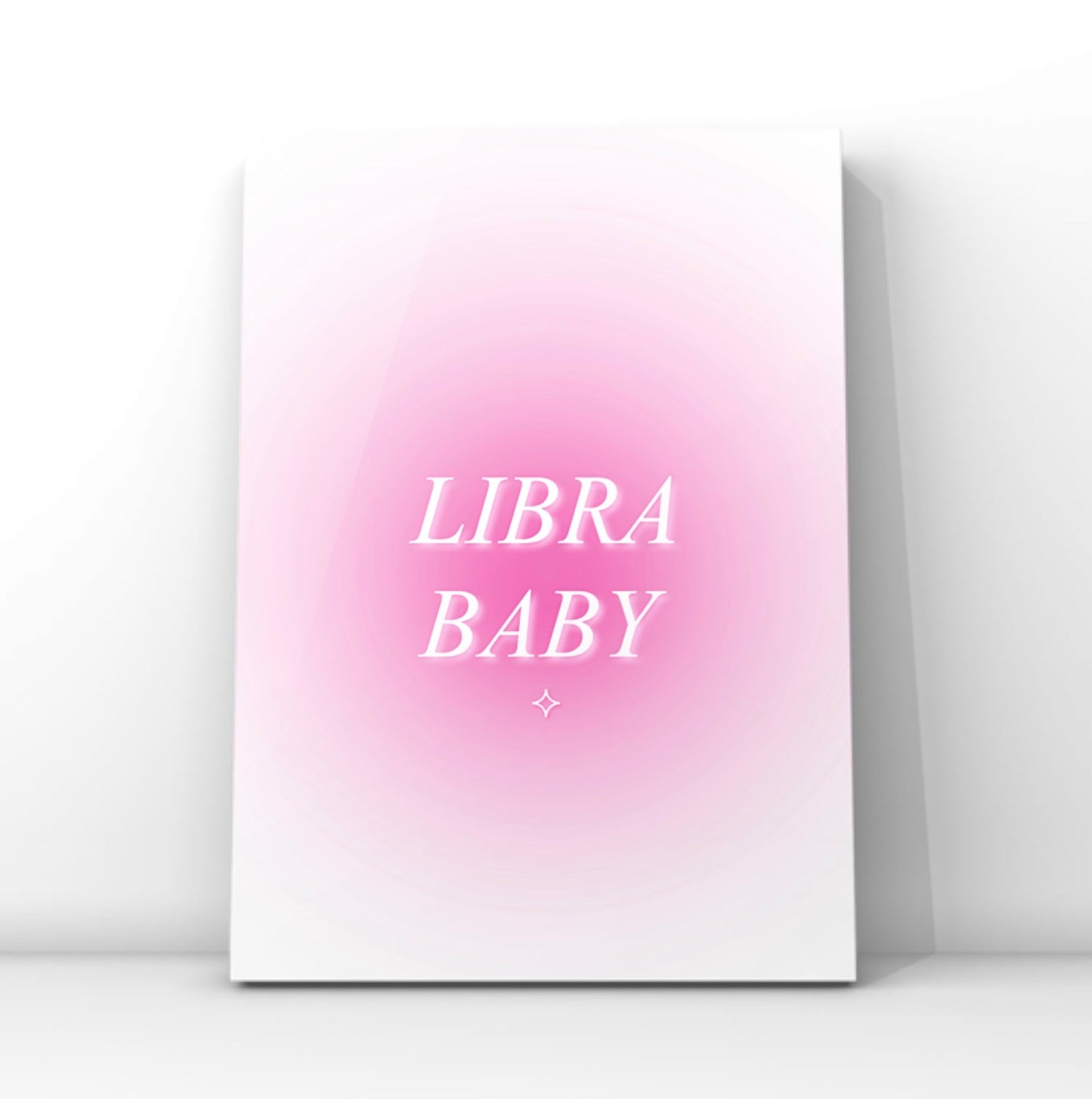 A vertical canvas art print featuring a pink gradient background with the words 'LIBRA BABY' in white serif lettering, displayed against a clean white wall.