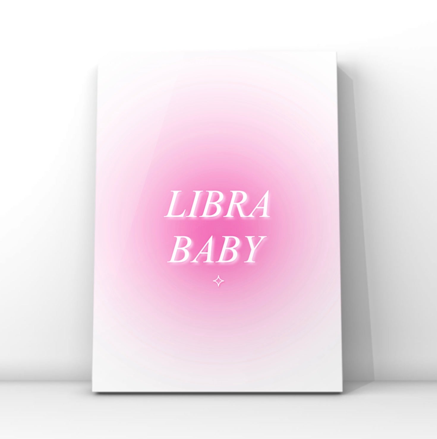 A vertical canvas art print featuring a pink gradient background with the words 'LIBRA BABY' in white serif lettering, displayed against a clean white wall.
