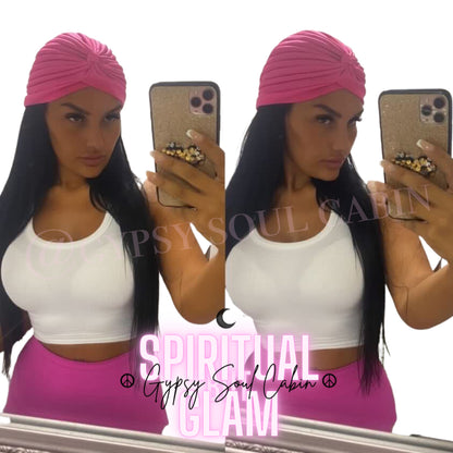 A woman wearing a pink Bohemian head wrap with a white top and pink trousers.