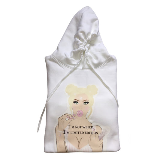 A white oversized hoodies with a graphic of a woman with blonde hair, holding a lollipop, and the text "I'M NOT WEIRD, I'M LIMITED EDITION" printed on the front. The design features pastel colours and a playful, artistic style.