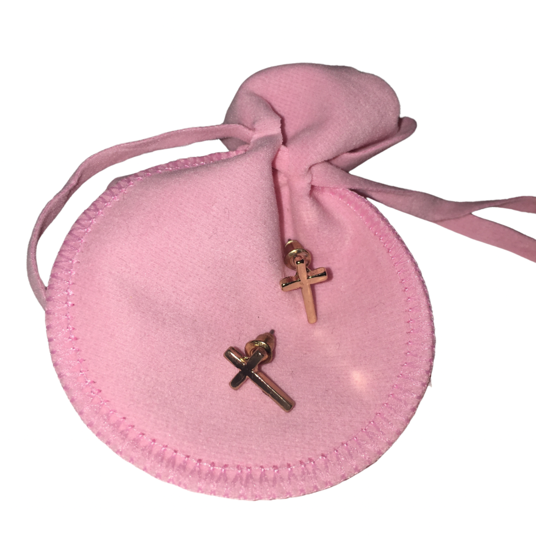 Two small gold-toned cross-shaped stud earrings displayed on a round pink drawstring pouch against a white background.