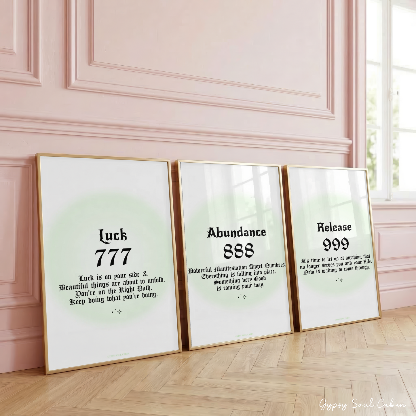 Set of three minimalist manifestation wall art prints featuring angel numbers 777, 888, and 999 in bold black gothic typography over a soft pastel green aura gradient backdrop, framed on a wooden floor against a pink panelled wall.