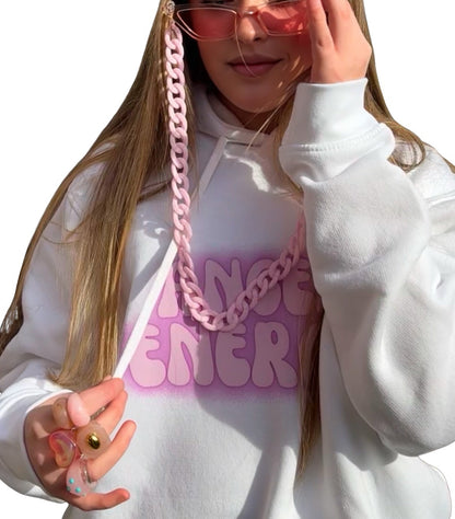 A young woman with long blonde hair wearing a white hoodie with a pink gradient 'ANGEL ENERGY' graphic and a chunky pink chain lanyard attached to Pink fashion glasses. She is also wearing 6 retro chunky rings posing against a solid white background.