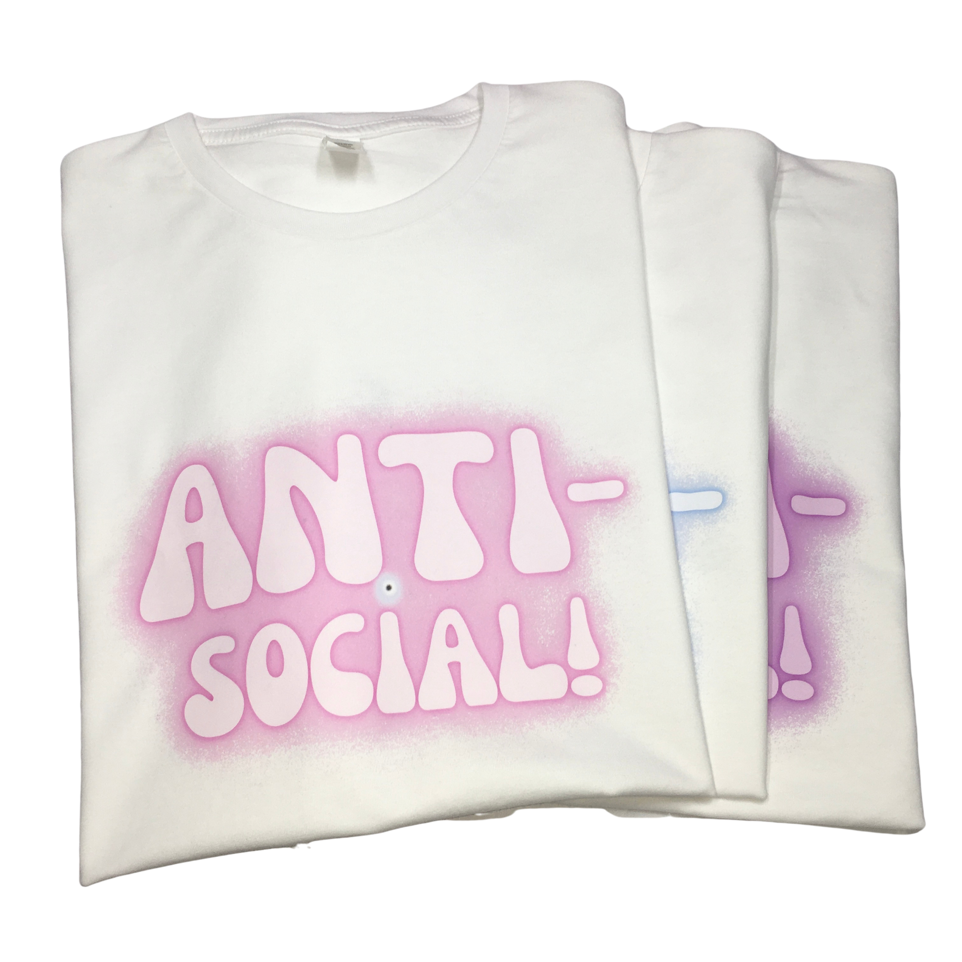 Three folded white T-shirts stacked, showing the Anti-Social slogan graphic and protective evil eye in different pink, blue, and purple spray-paint halo airbrush colour variants.