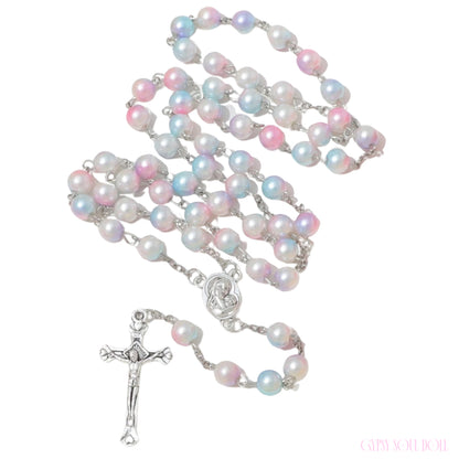 A rosary necklace featuring iridescent pastel pearls in pink, blue, and white, connected by silver-tone chains and a silver-tone crucifix pendant, shown on a plain white background.