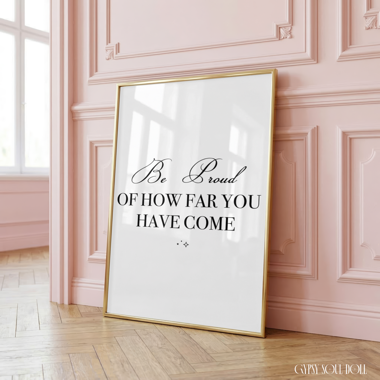 Elegant monochrome self-care wall art combining a fluid cursive script text for Be proud with two tiny, centred celestial sparkle details below.