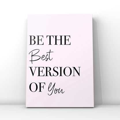 Minimalist pink affirmation print reading Be The Best Version Of You in a combination of crisp black serif and cursive script fonts, leaning against a clean white wall backdrop.