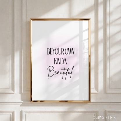 Sleek black typography motivational print displaying the text Be Your Own Kinda Beautiful centred over a soft blush pink aura gradient background.