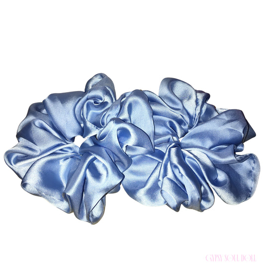 A set of two light blue satin hair scrunchies arranged on a plain white background.