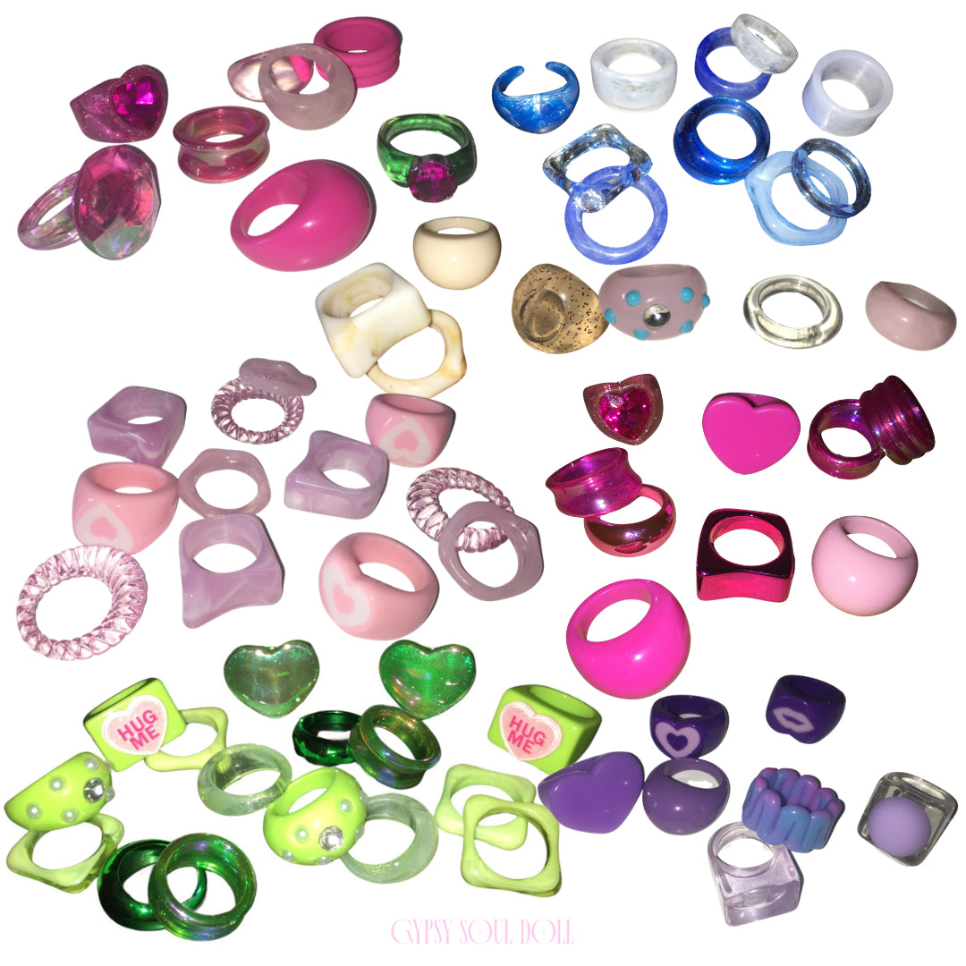 A massive colourful flat lay collection of Candy Land style acrylic resin rings from Gypsy Soul Doll, featuring candy pinks, neon greens, electric blues, deep purples, and pastel lilac statement rings scattered across a white background.