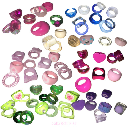 A massive colourful flat lay collection of Candy Land style acrylic resin rings from Gypsy Soul Doll, featuring candy pinks, neon greens, electric blues, deep purples, and pastel lilac statement rings scattered across a white background.