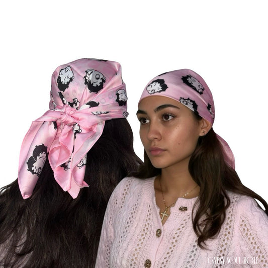 Studio compilation view showcasing a pink headscarf printed with retro cartoon girl graphics, worn tied around a model's head from the front and knotted over long dark hair from the back.