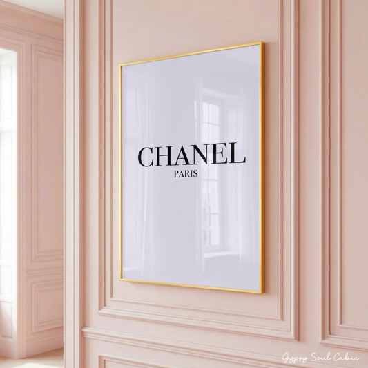 Minimalist Chanel Paris typography art print in a large gold frame hanging on a classic panelled pink wall.