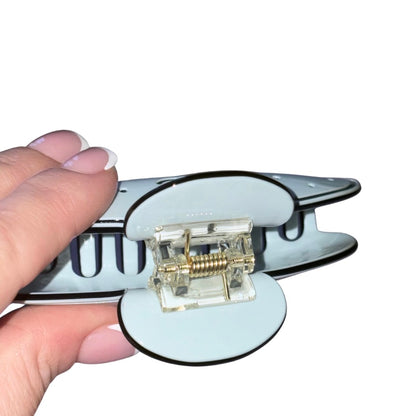 A hand hoding a Chanel hair clamp.