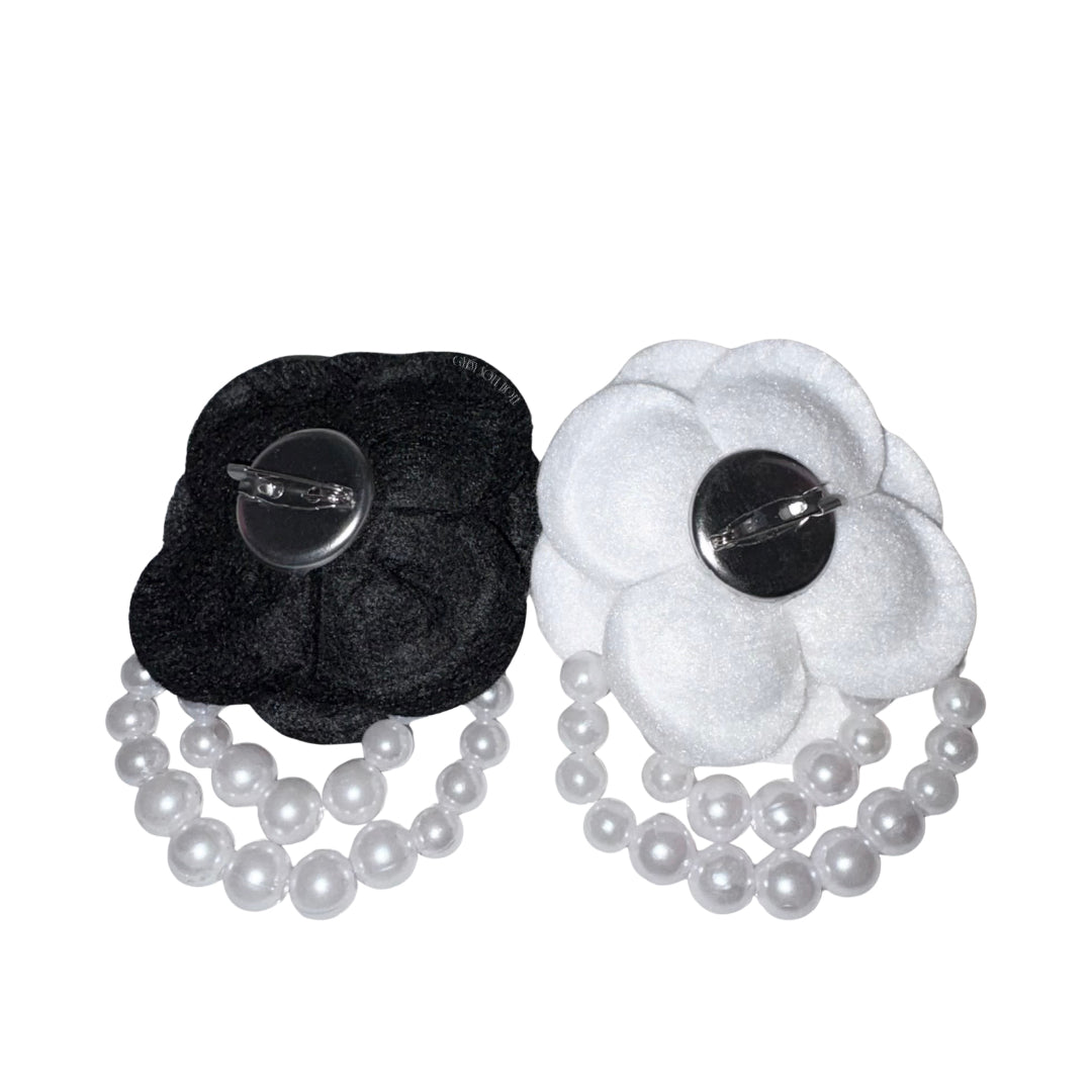 Back view of the black and white fabric camellia brooches displaying the secure silver metallic dual pin mechanism with a safety clasp and a hair clip option.