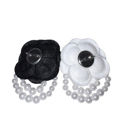 Back view of the black and white fabric camellia brooches displaying the secure silver metallic dual pin mechanism with a safety clasp and a hair clip option.