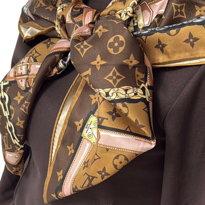 Rear view of a woman showcasing the classic pointed drape of a brown monogram silk square scarf styled elegantly over her shoulders.