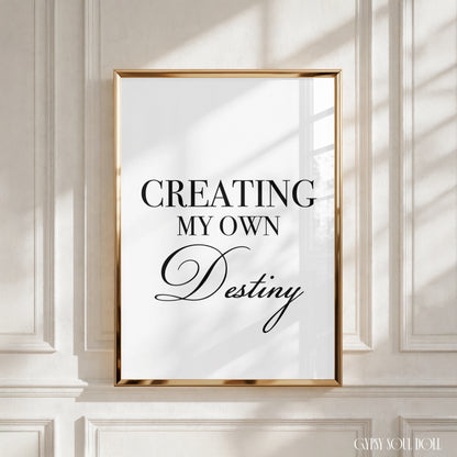 A framed typographic wall art print with the text 'CREATING MY OWN Destiny' in black lettering on a white background, mounted against a cream panelled wall with soft window shadows by Gypsy Soul Doll.