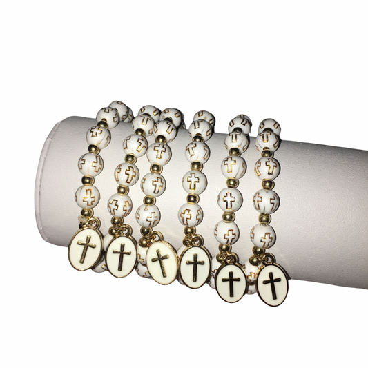 Six white beaded rosaries with gold-tone metal accents and oval cross pendants, arranged on a white cylindrical display stand against a white background.