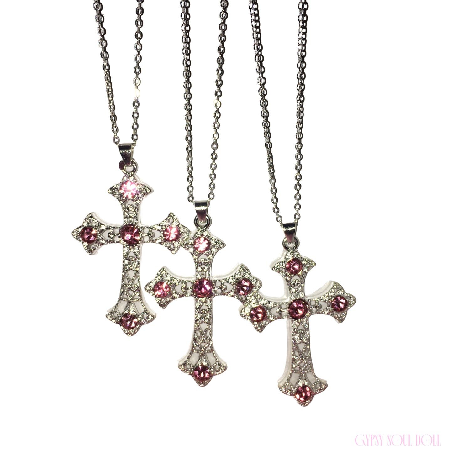 Three silver cross pendant necklaces with pink gemstone accents, displayed on a clean white background.