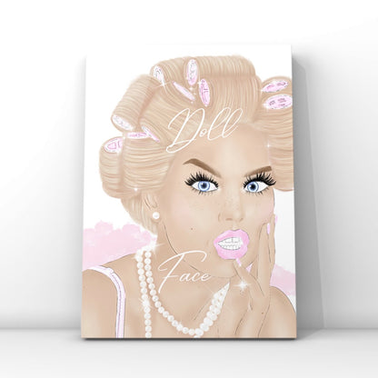 A vertical wall art print featuring a stylised illustration of a glam blonde woman with pink hair curlers, blue eyes, long lashes and pink lips, with the words 'Doll Face' written across the artwork by Gypsy Soul Doll. The glam print is shown leaning against a white wall on a light grey floor.