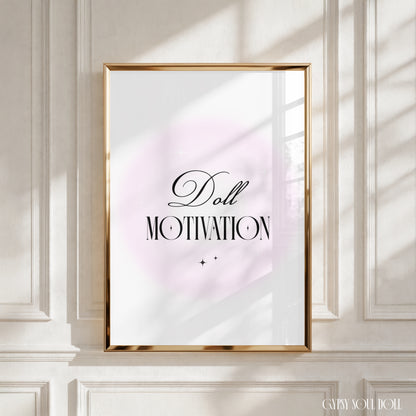 A framed typographic wall art print with the words 'Doll MOTIVATION' in black script and serif lettering over a soft pale pink circular backdrop, displayed against an off-white panelled wall with warm window light casting shadows by Gypsy Soul Doll.