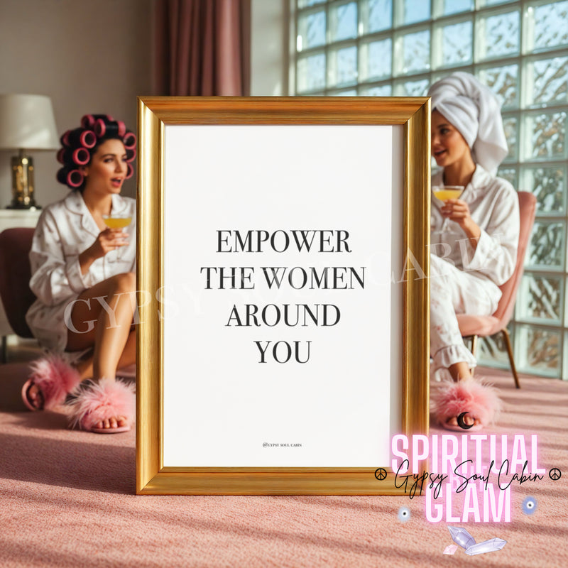 Minimalist black and white typography wall art print with the text Empower The Women Around You in a gold frame, set against a glam dressing room background with women in robes and hair rollers.
