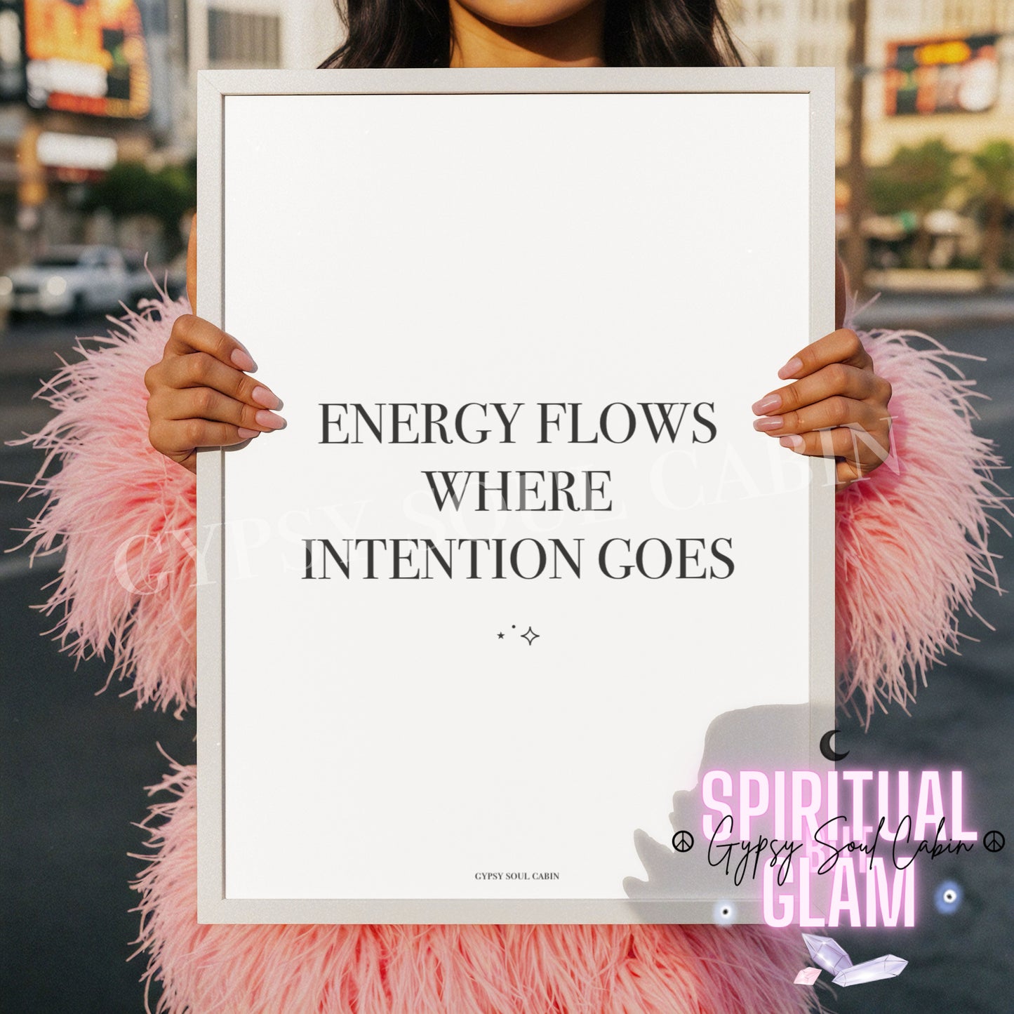 Minimalist black and white A4 typography print featuring the Law of Attraction quote Energy Flows Where Intention Goes, held by a woman in a pink fluffy coat.
