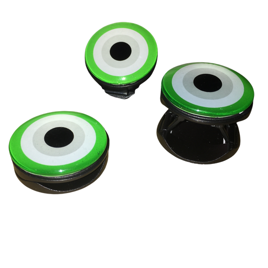 Product shot displaying three expanding green cosmic evil eye phone grips on a white background, showcasing the glossy top surface and black accordion base.