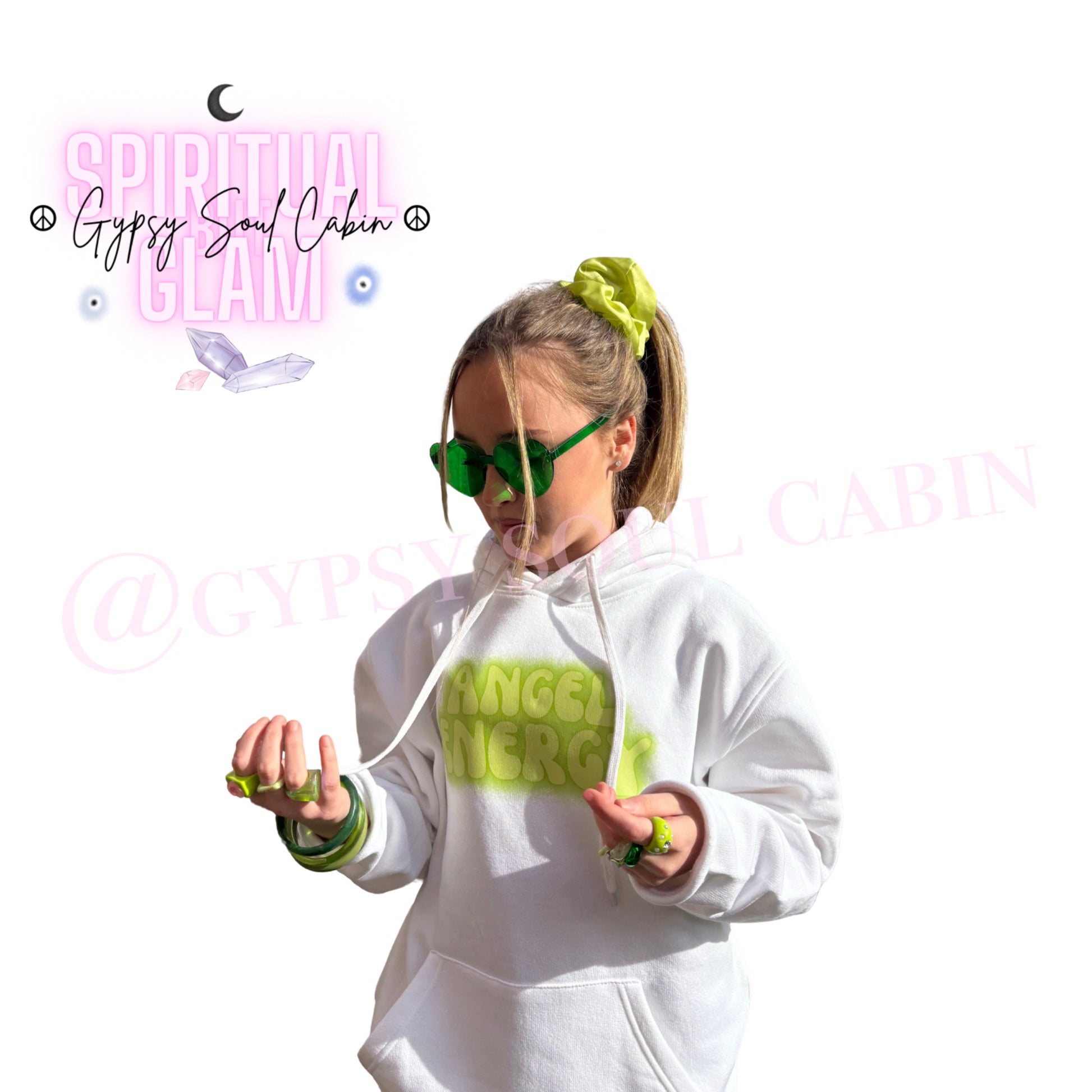 Model showcasing green heart-shaped glasses paired with matching green bangles, chunky rings, a hair scrunchie, and an Angel Energy hoodie by Gypsy Soul Cabin.