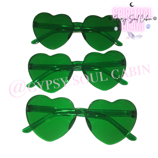 Three pairs of translucent green heart-shaped rimless fashion sunglasses stacked vertically against a white background with a pink crystal logo