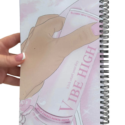 Reverse side of the glossy pink notepad cover displaying an original graphic of a hand holding a Vibe High energy drink with the text Flushes Away Negativity.