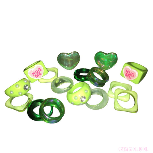 Studio flat lay of the Gypsy Soul Doll limited edition set of 8 retro resin rings featuring lime green Hug Me conversation hearts, glossy emerald bands, and pearl-studded acrylic styles.