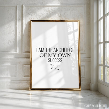 A framed motivational poster with the text 'I AM THE ARCHITECT OF MY OWN SUCCESS' in black serif font on a white background, enclosed in a thin gold frame and leaning against a white panelled wall near a window by Gypsy Soul Doll.
