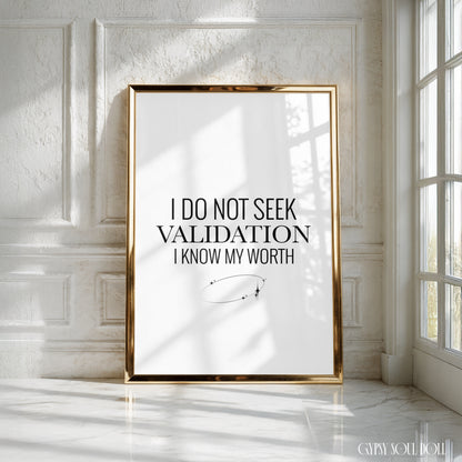 A framed motivational art print with the text 'I DO NOT SEEK VALIDATION I KNOW MY WORTH' in a black serif font on a white background, enclosed in a thin gold frame. The print is leaning against a white panelled wall in a bright room, with natural window light casting shadows, by Gypsy Soul Doll.