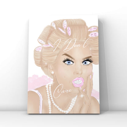 A vertical wall art print featuring a stylised illustration of a blonde woman with pink hair curlers, blue eyes, long lashes and pink lips, with the words 'I Don't Care' written across the portrait by Gypsy Soul Doll. The glam print is shown leaning against a white wall on a light grey floor.