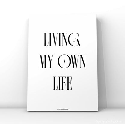 Minimalist black and white typography quote print featuring the text Living My Own Life with small star graphic elements inside the letters.